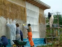 Lime render application: mechanically sprayed and manually pressed into straw substrate.